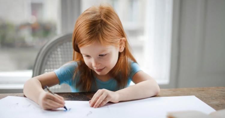 Kleines Mädchen sitzt am Tisch und malt