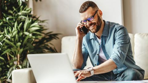 Mann arbeitet am Laptop und telefoniert