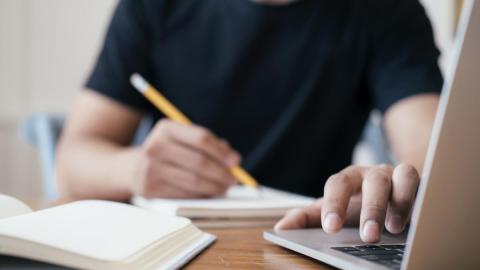 mann sitzt vor laptop und lernt online